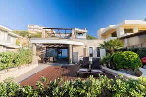 Una villa moderna con terrazza in legno, posti a sedere all'aperto e vista sugli edifici circostanti.