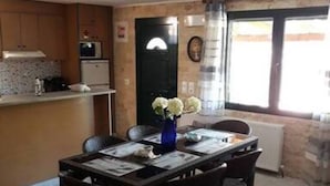 A dining area with a table set for four, a vase with flowers, and a kitchen in the background. - Villa Smaro With Private Pool (Chania)