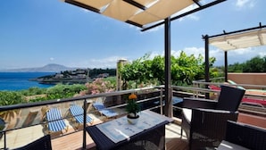A terrace with wicker furniture, a table with a plant, and a view of the sea and mountains. - Villa Smaro With Private Pool (Chania)