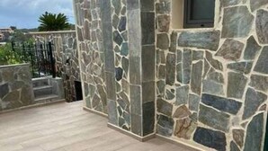 A stone-clad building with a tiled patio area. - Villa Smaro With Private Pool (Chania)
