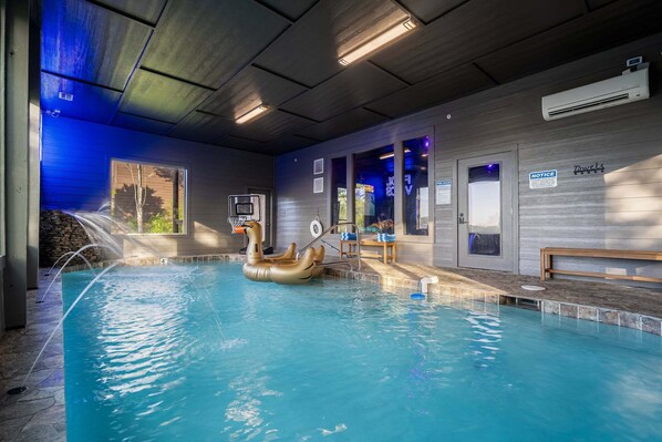 An indoor swimming pool with a swan float, a basketball hoop, and a notice board.