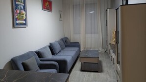 A modern living room with a grey sofa, a marble coffee table, and a cabinet with a clock.