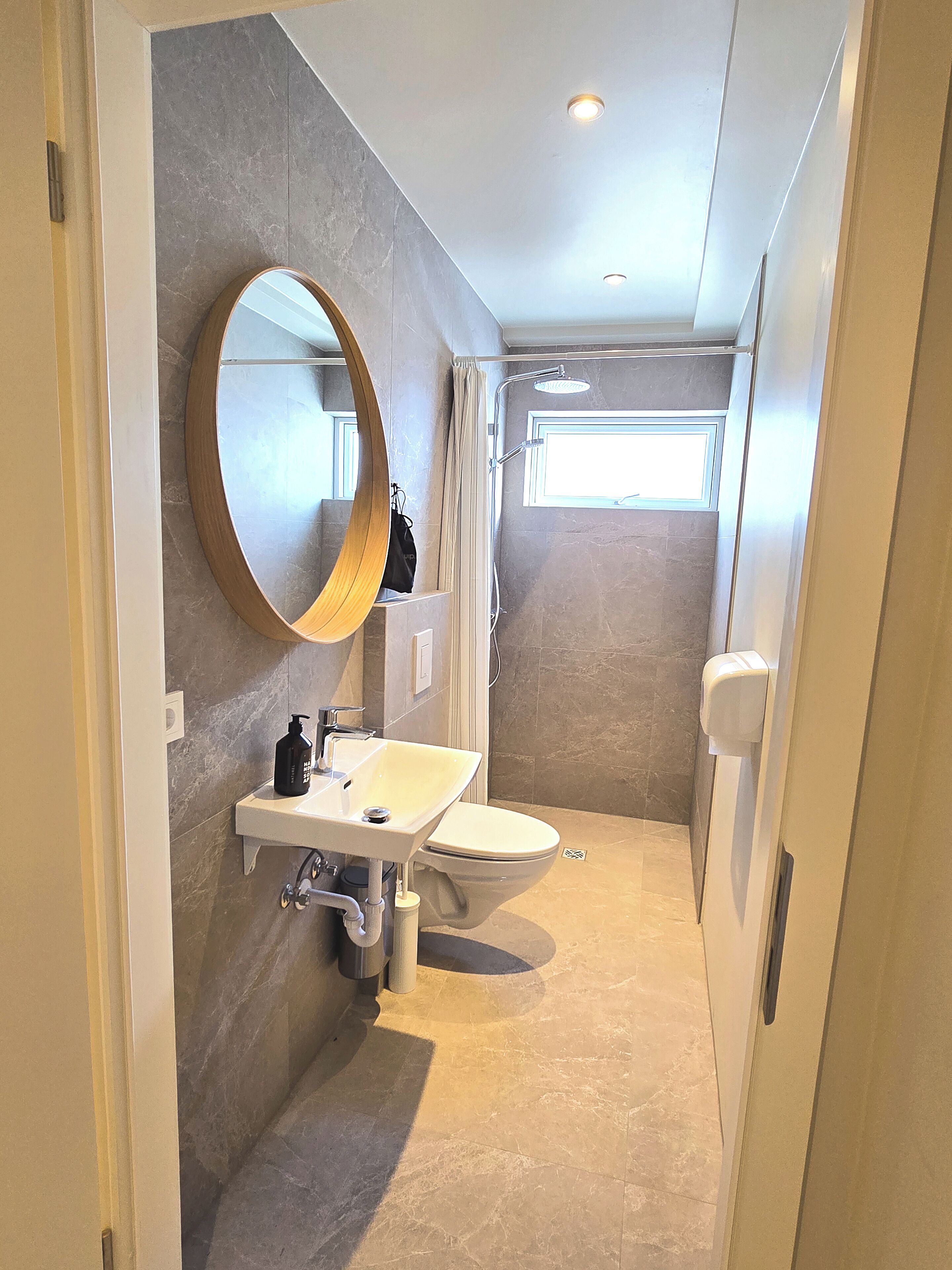 A modern bathroom with a large mirror, a sink, a toilet, and a shower area.