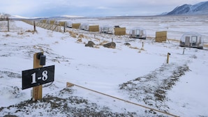 A row of transparent dome structures labeled 1-8, set in a snowy landscape with mountains in the background.