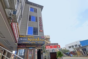 Un edificio a più piani con un cartello che indica Hotel Maharaja, un ristorante per famiglie con sala per feste e bar.