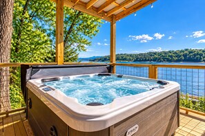 Een hottub op een houten terras met uitzicht op een meer en bergen.