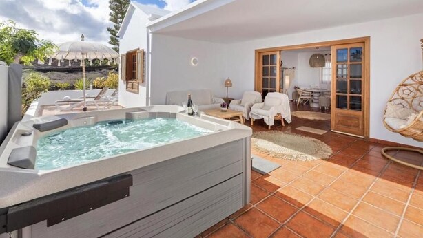 A modern outdoor living area with a hot tub, lounge chairs, and a patio with a view of the landscape. - Casa del Mar. Spectacular villa with sea views and jacuzzi in Charco del Palo (Chraco del Palo - Haría)