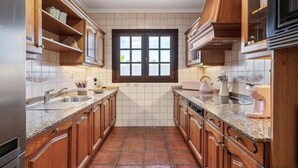 A kitchen with wooden cabinets, granite countertops, a double sink, and a window with a view. - Casa del Mar. Spectacular villa with sea views and jacuzzi in Charco del Palo (Chraco del Palo - Haría)