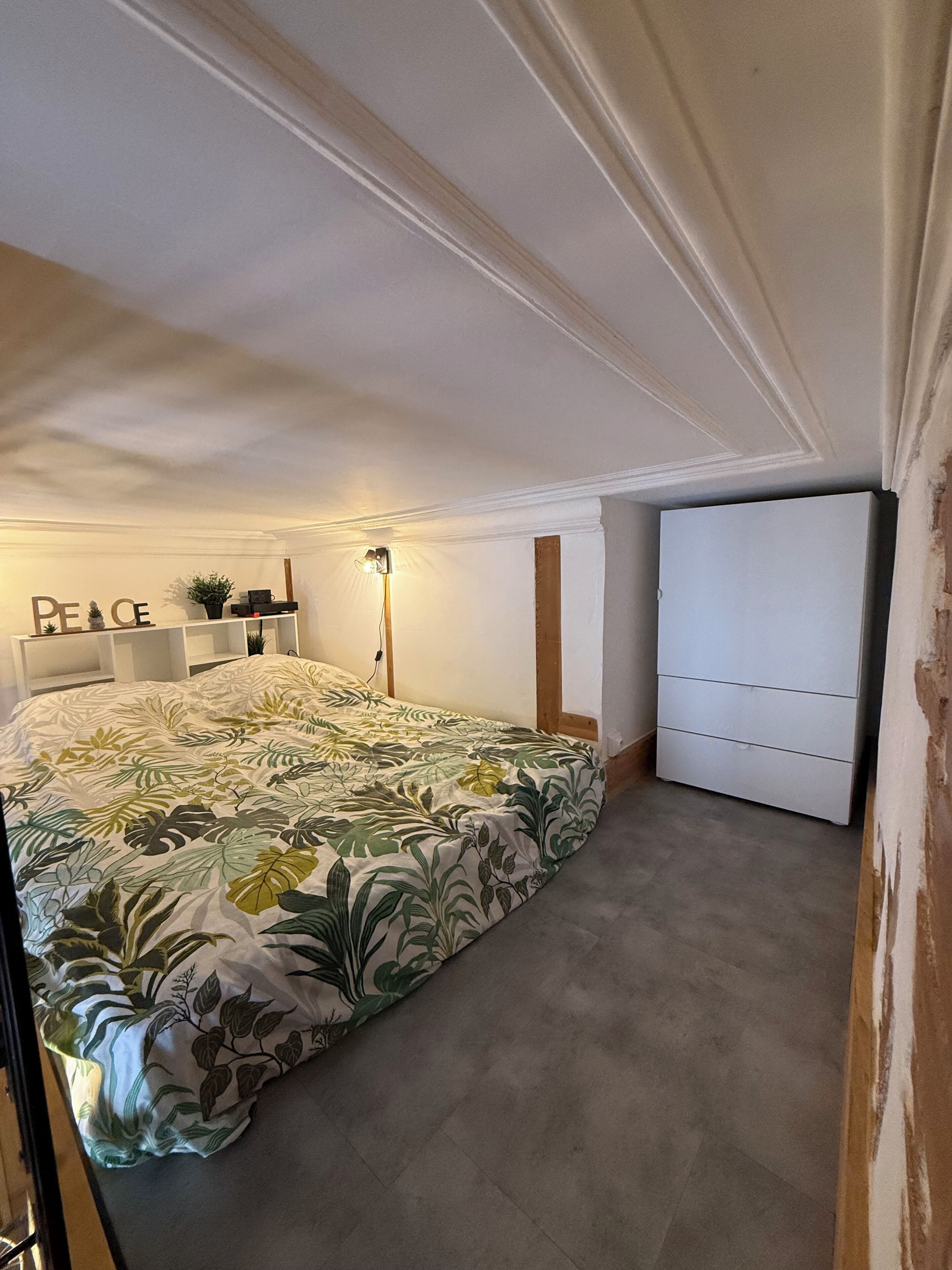 A bedroom with a bed, a nightstand, a lamp, and a wardrobe.
