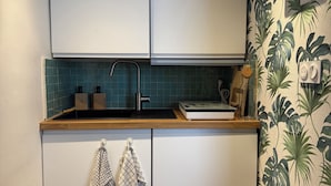 A compact kitchen with white cabinets, a tiled backsplash, and a wooden countertop. - "L'esprit Sable & Détente " Cosy studio between sea and port (Les Sables-d'Olonne)