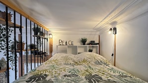 A bedroom with a bed, a shelf with plants, a wall with 'PEACE' decor, and a railing with plants. - "L'esprit Sable & Détente " Cosy studio between sea and port (Les Sables-d'Olonne)