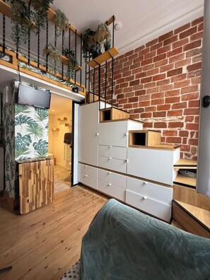 Ein modernes Wohnzimmer mit einer Ziegelwand, Holzdielen, einem weißen Schrank und einem grünen Sofa.