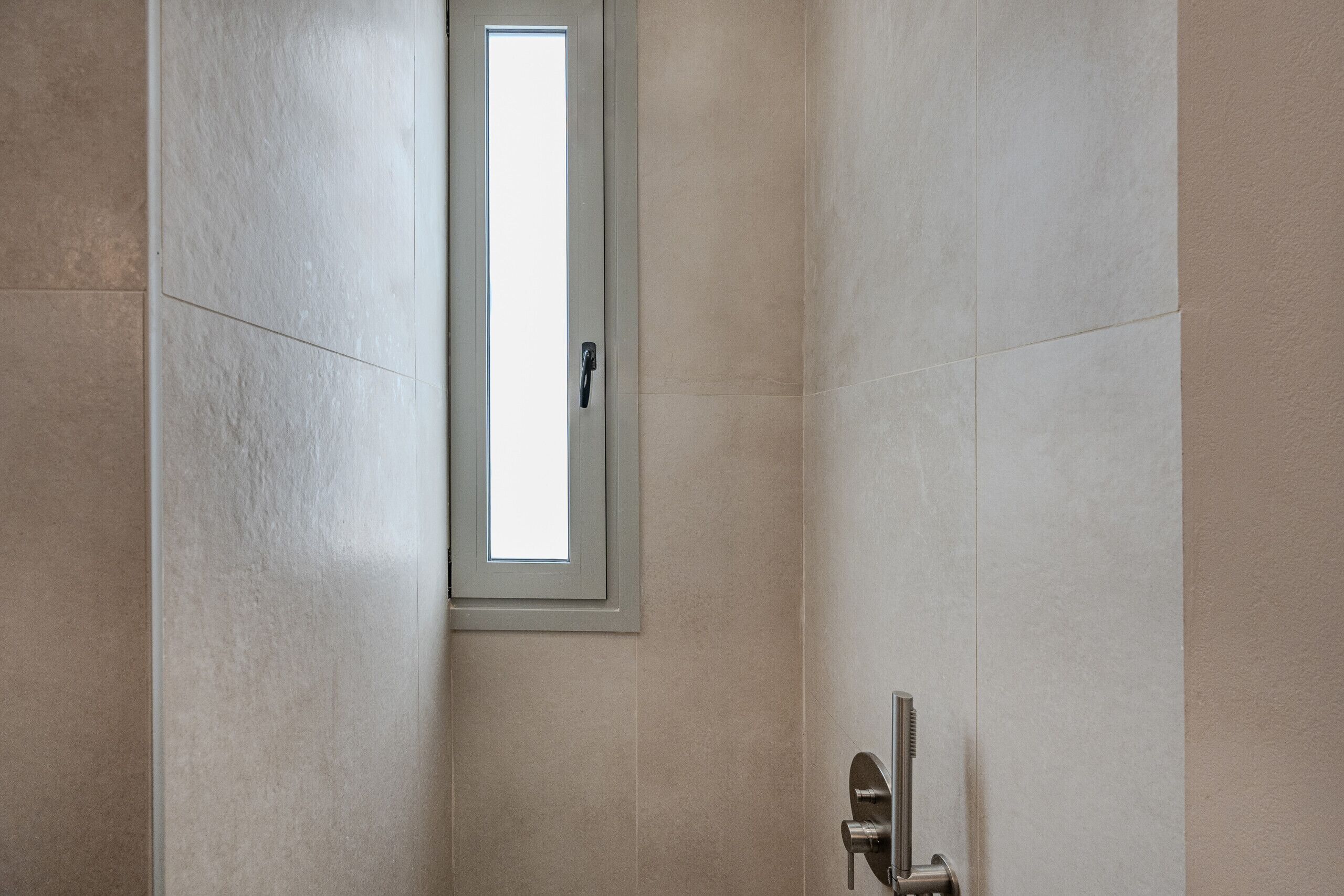 Ein Badezimmer mit Dusche, Fenster und Tür.