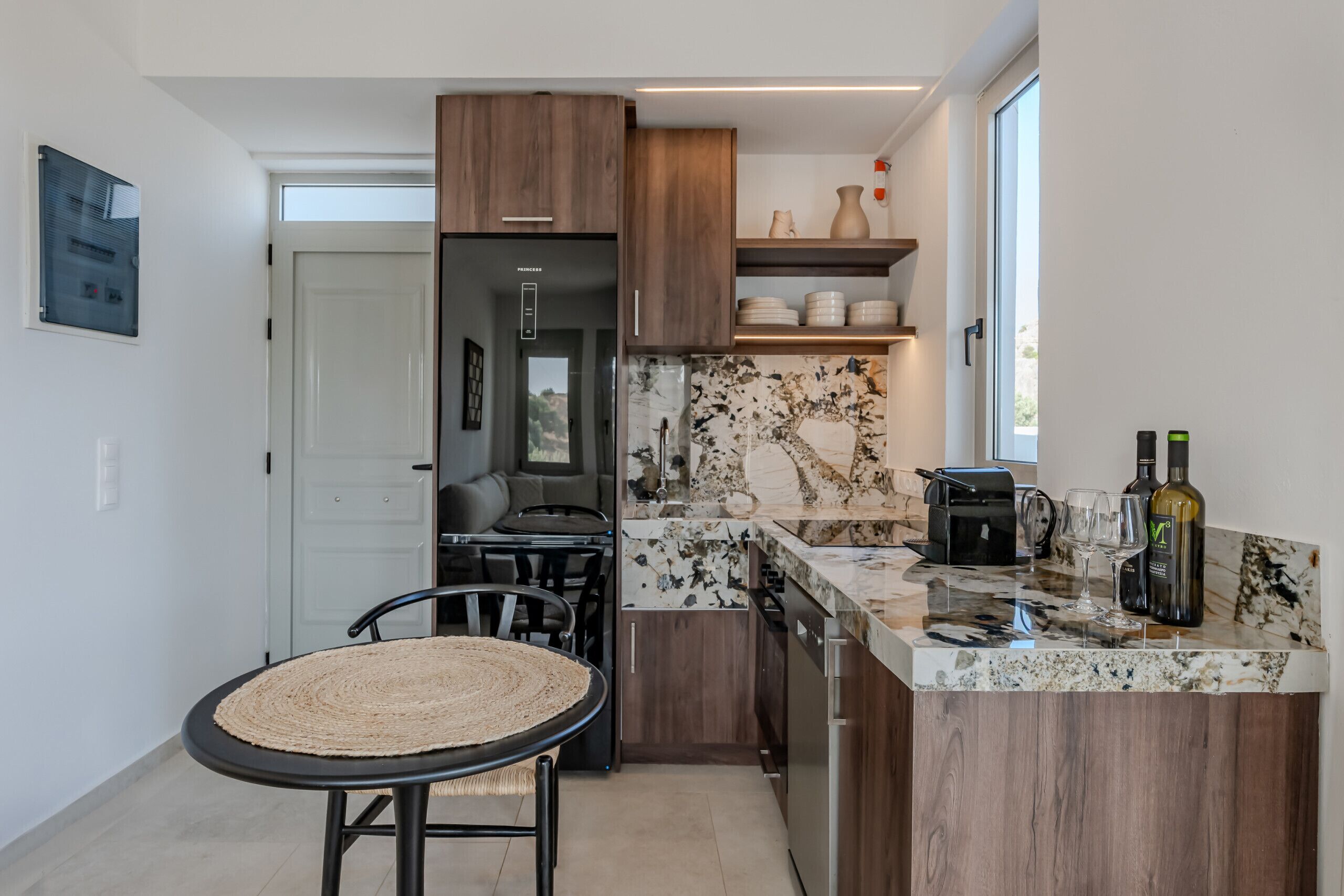 Une cuisine moderne dotée d’un plan de travail en marbre, de meubles en bois et d’un coin repas avec une chaise en osier.