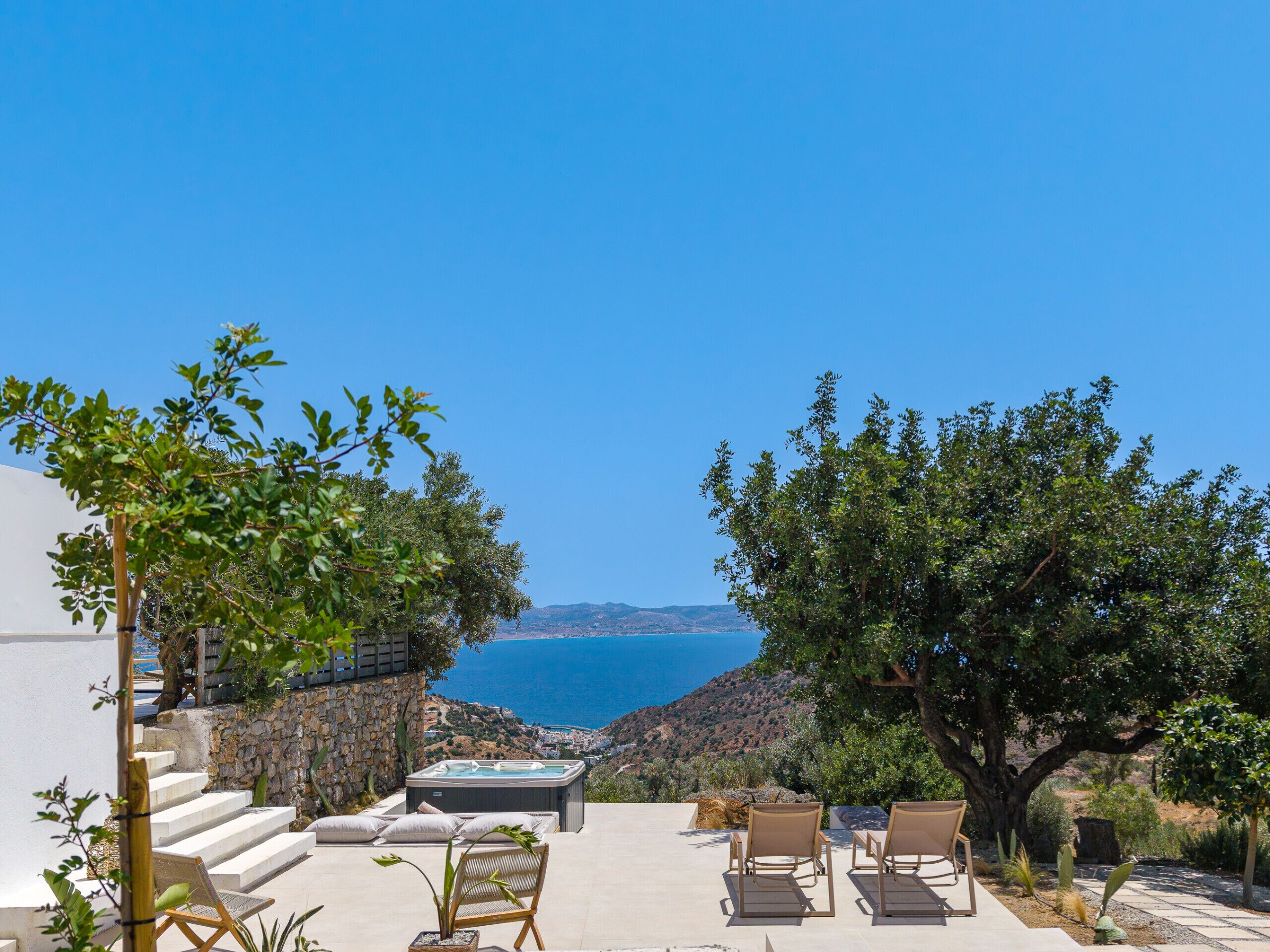 A terrace with outdoor seating, a hot tub, and a view of the sea.