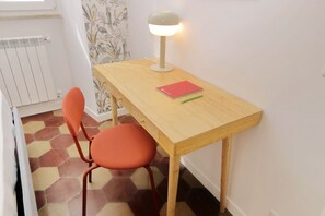 A small, neatly arranged room with a wooden desk, a chair, a lamp, and a radiator. - Lovely two-bedroom apartment near vatican  (Roma)