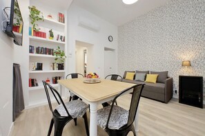 A modern living room with a dining table, chairs, a sofa, a fireplace, and a bookshelf with books and plants. - Lovely two-bedroom apartment near vatican  (Roma)