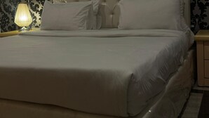 A neatly made bed with a tufted headboard, a bedside lamp, and a framed picture on the wall.