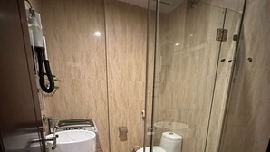 A modern bathroom with a glass-enclosed shower, a standalone bathtub, a toilet, and a sink with a marble countertop.