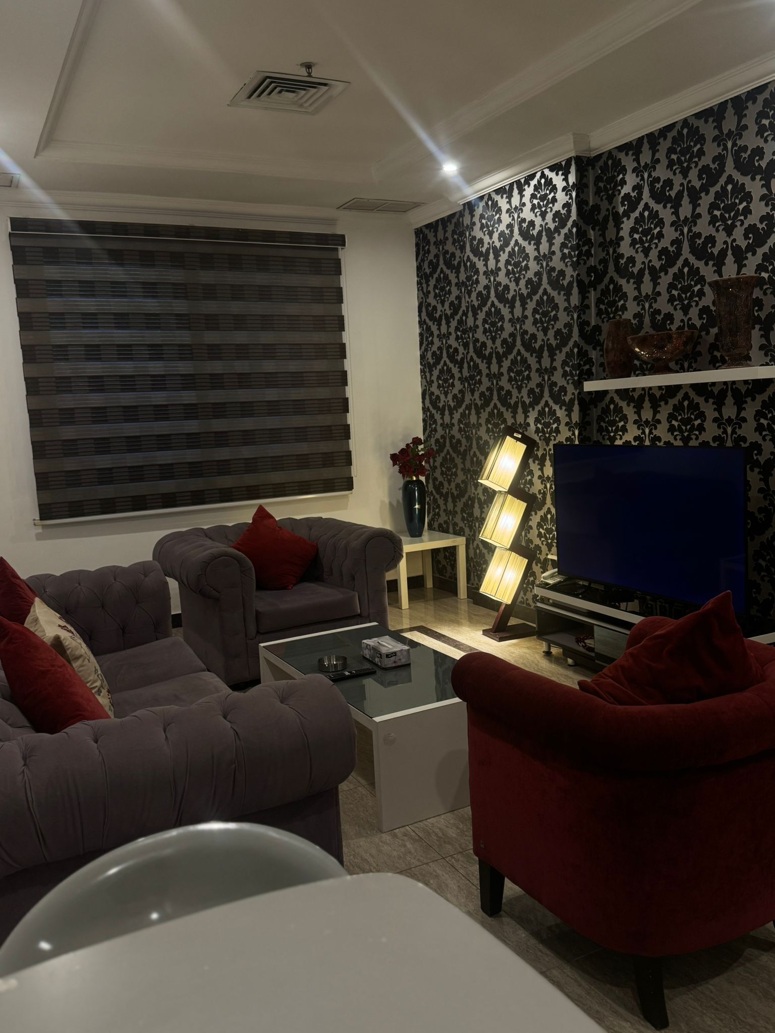 Ein modernes Wohnzimmer mit einer Sofagarnitur, einem Couchtisch, einem Fernseher und einer dekorativen Lampe.