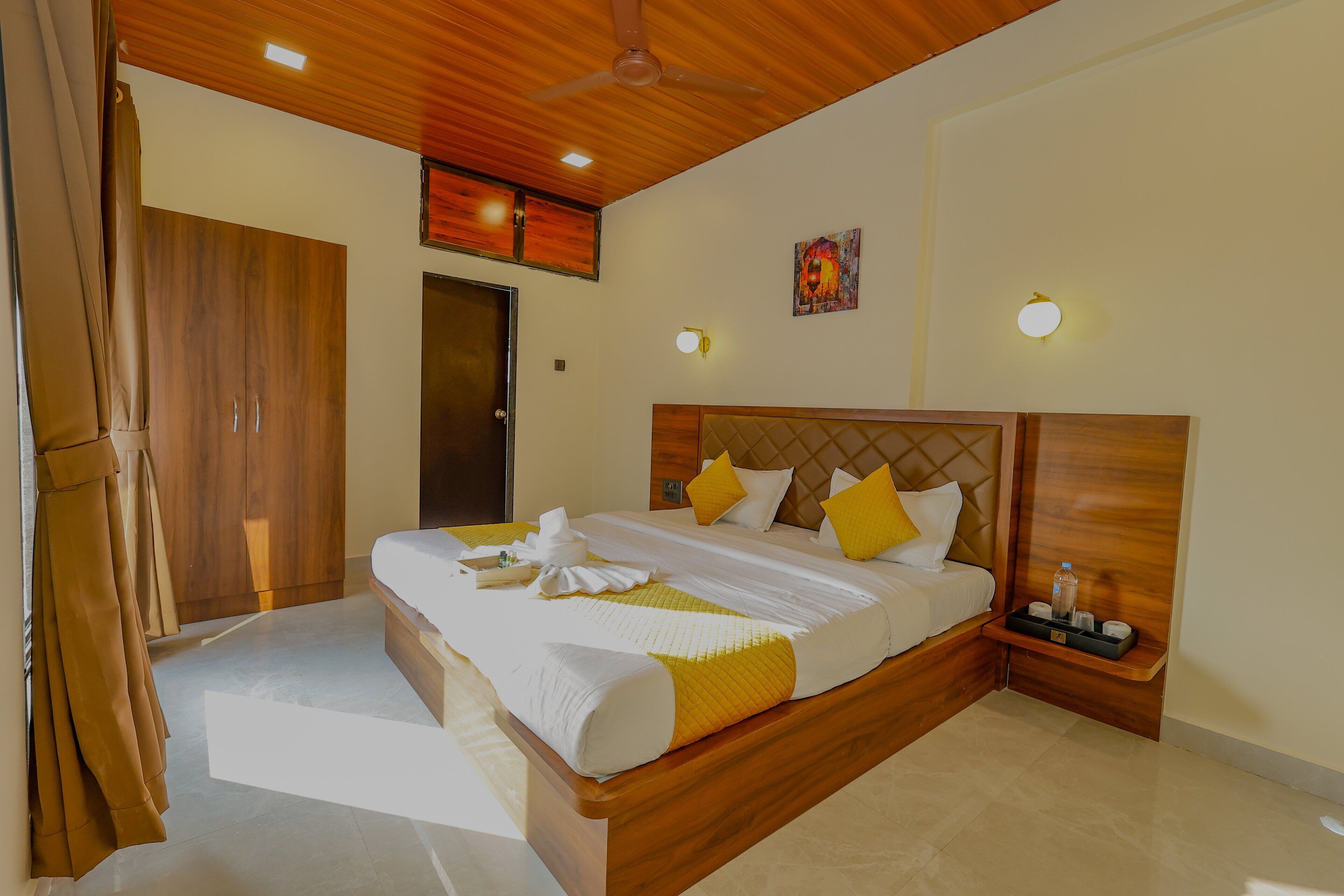 A hotel room with a wooden bed, a nightstand, a wardrobe, and a ceiling fan.