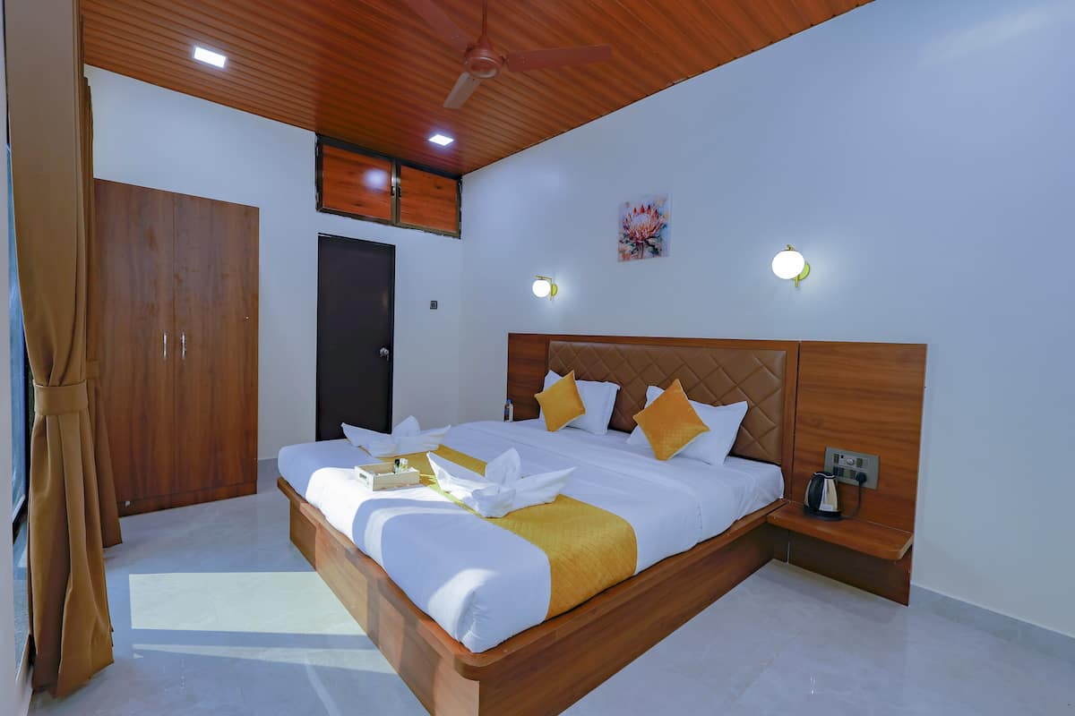 Un dormitorio amplio con una cama grande, cabecera de madera y una mesita de noche con hervidor.