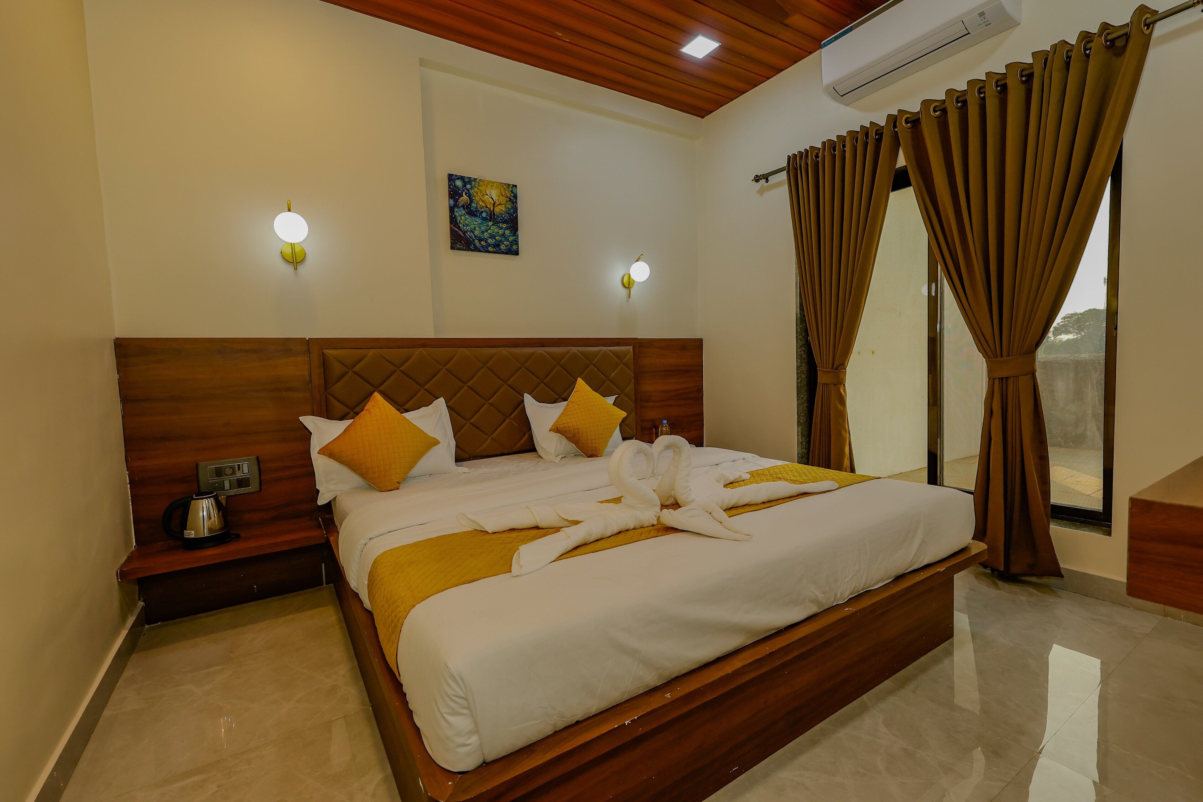 A hotel room with a wooden headboard, a bed with white and yellow bedding, two bedside tables with lamps, and a painting on the wall.
