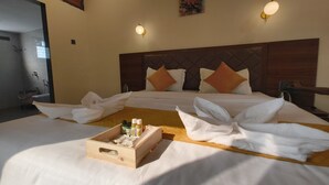 Ein Hotelzimmer mit zwei Betten, einem Holzkopfteil, einem Bild an der Wand und einem Tablett mit Pflegeprodukten.
