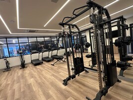Un gimnasio con cintas de correr, máquinas de pesas y pesas sueltas.
