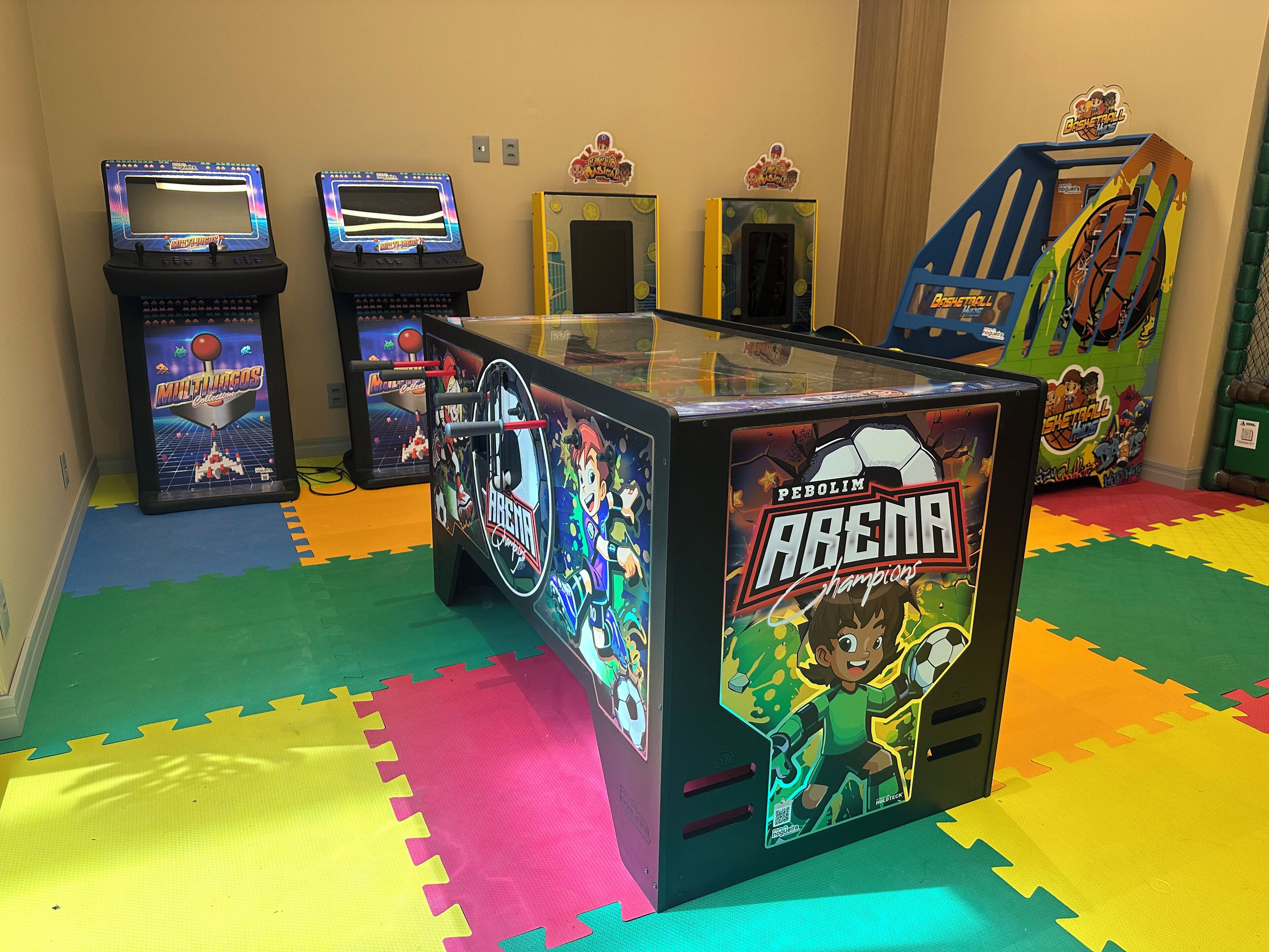Zona de juegos infantiles con juegos de arcade y una estructura temática de baloncesto.