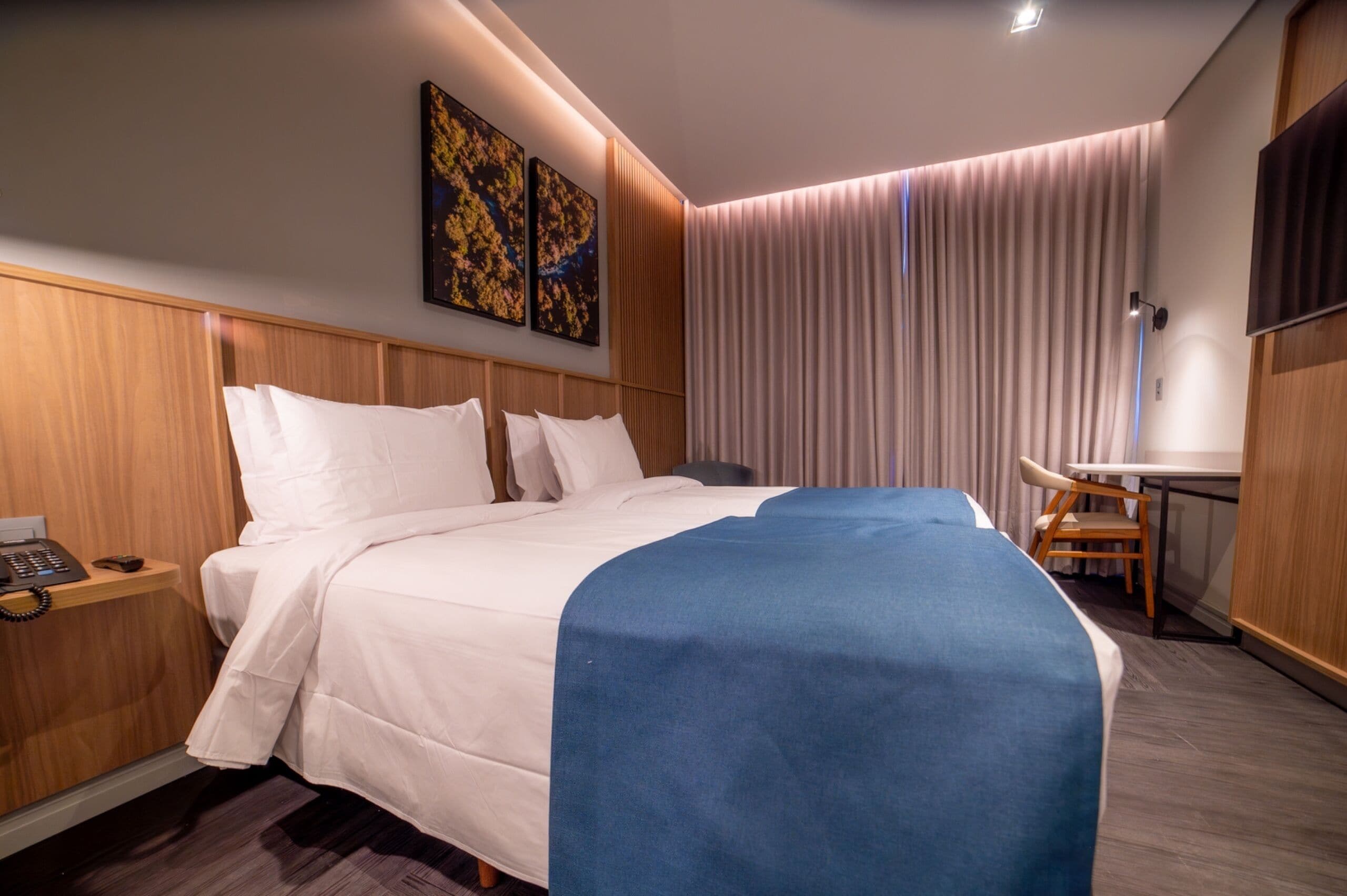 A modern hotel room with a large bed, a desk, and a flat-screen TV.