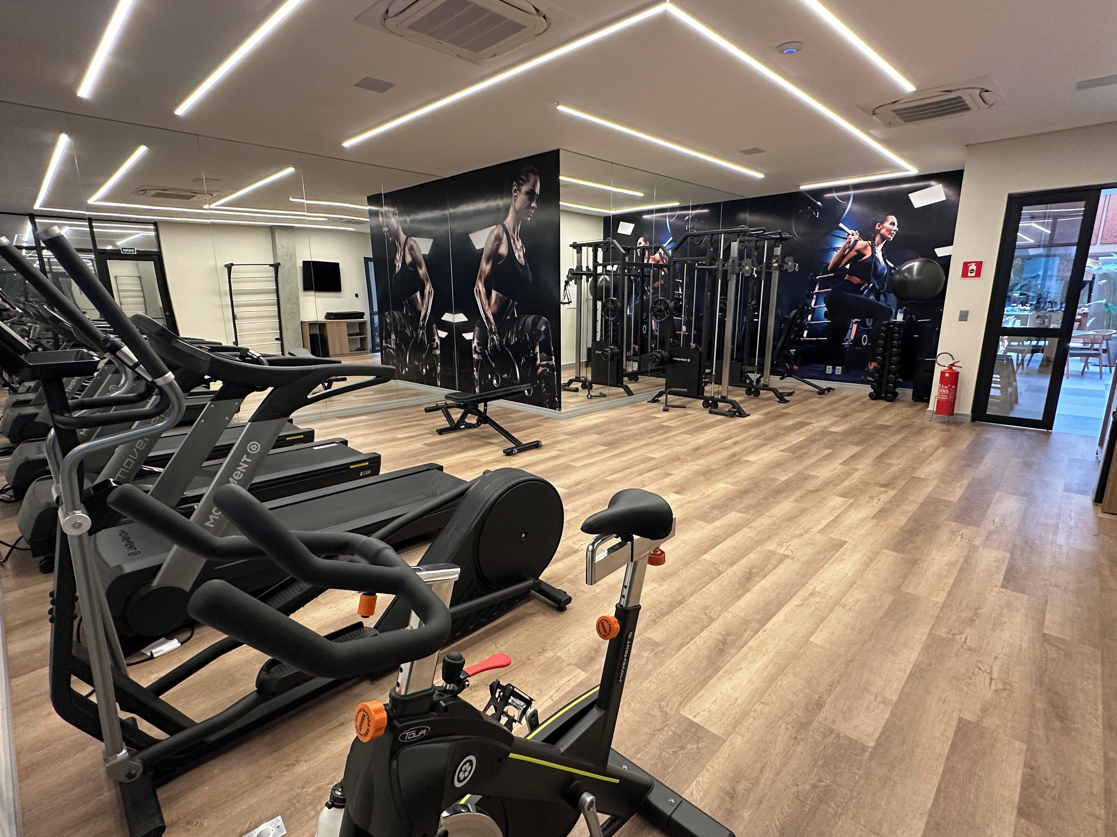 A gym with multiple treadmills, weight machines, and a mirror wall.