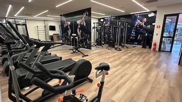 A gym with multiple treadmills, weight machines, and a mirror wall.