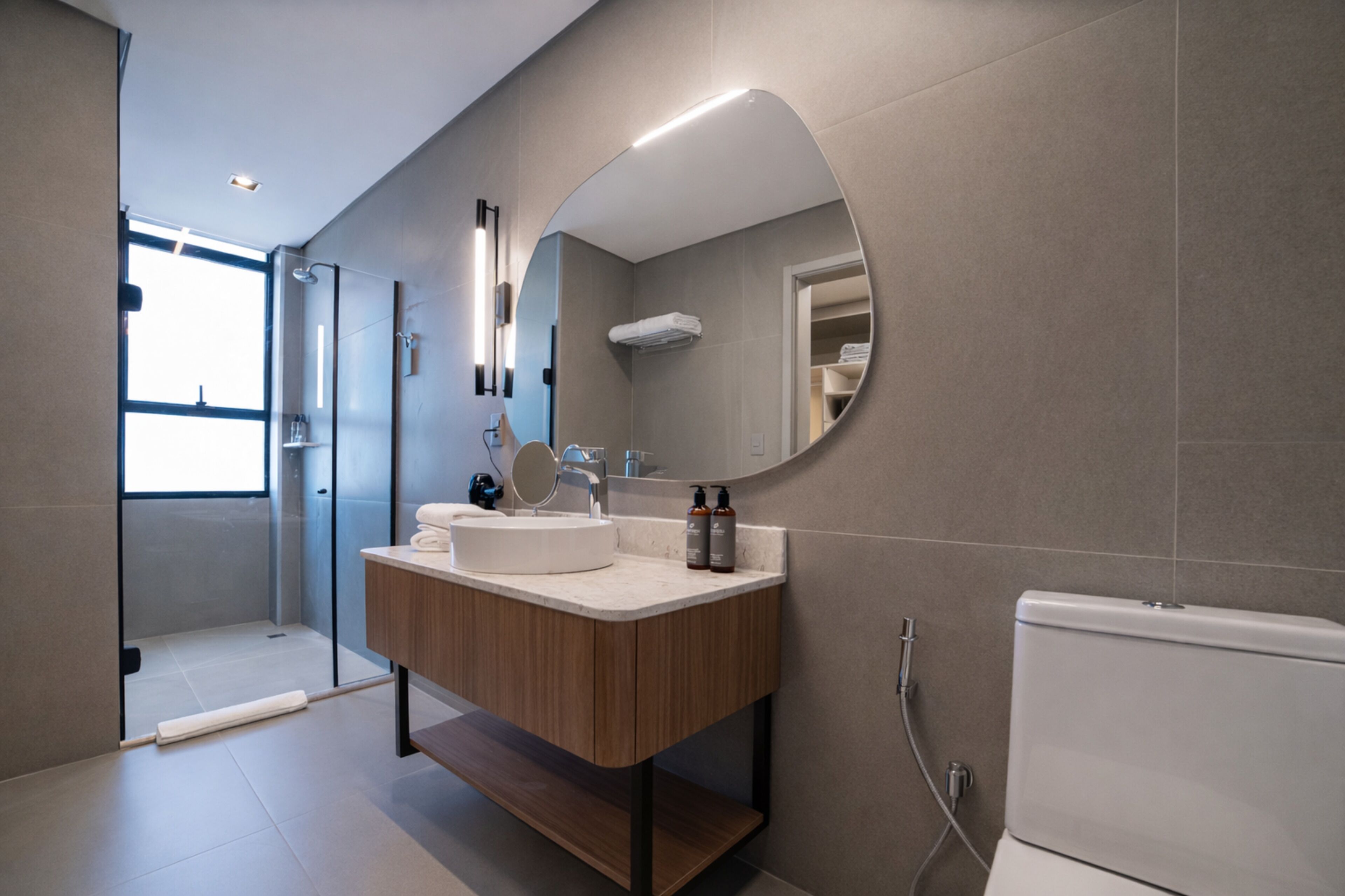 A modern bathroom with a large mirror, a sink, and a toilet.