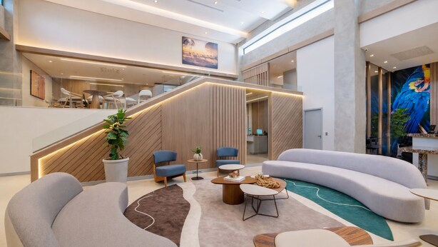 Un hall d’entrée moderne avec un canapé incurvé, une table basse et un escalier.