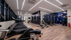 Une salle de sport équipée de tapis de course, d’appareils de musculation et d’un grand mur entièrement recouvert de miroirs.