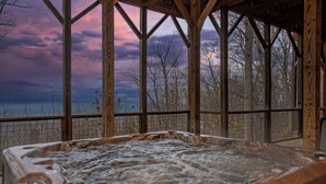 A hot tub with a view of a forest and a cloudy sky. - Mountain Cascades: Pool*Views*Theater*Games*Wifi*HotTub*Luxury (Sevierville)