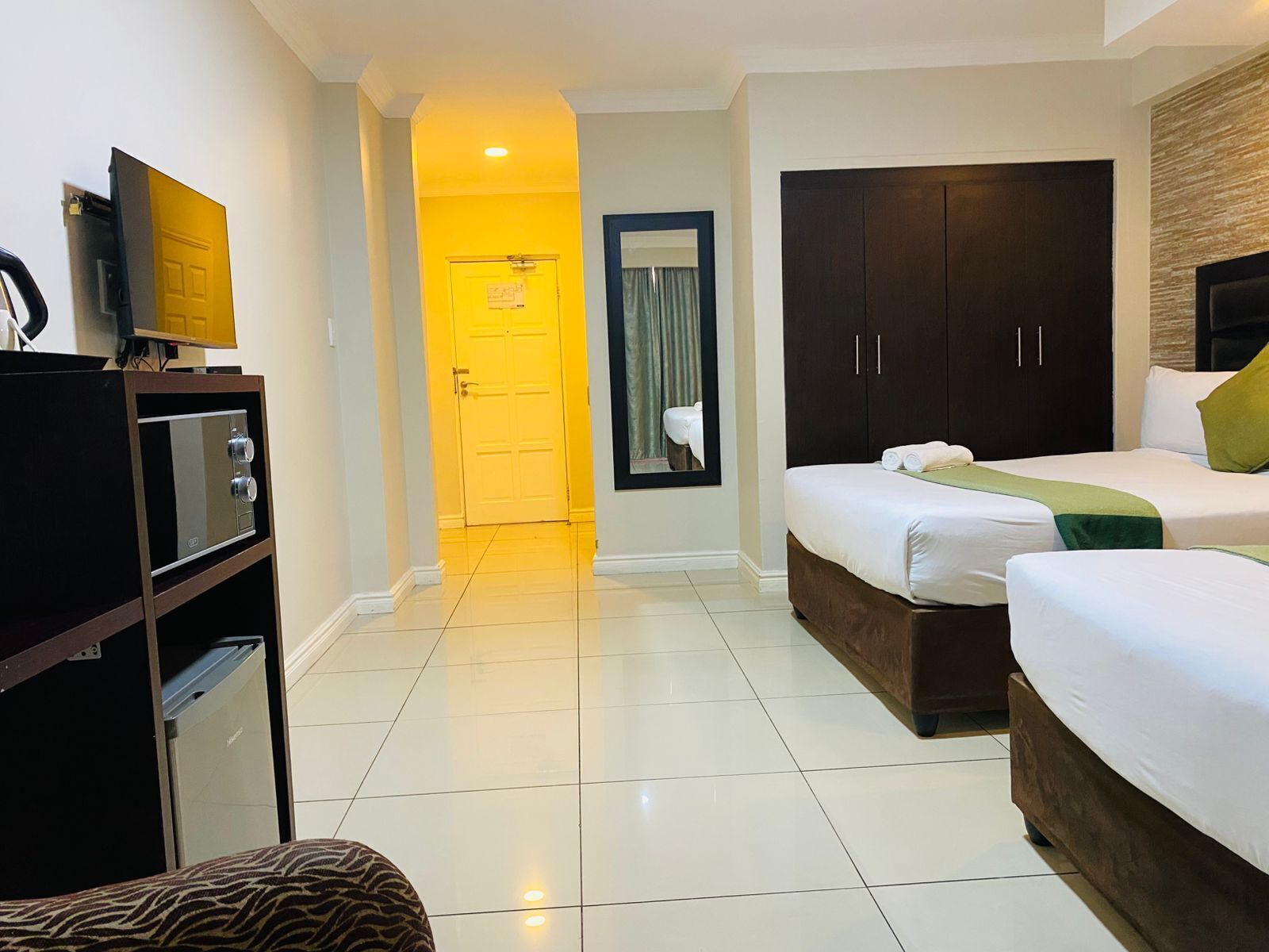 Una habitación de hotel con una cama, un armario, un televisor y un baño visible a través de una puerta.