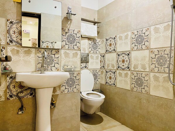 A bathroom with a sink, toilet, and a mirror. The walls are tiled with patterned designs. - Hotel November, At Zirakpur Bus Stand (Dera Bassi)