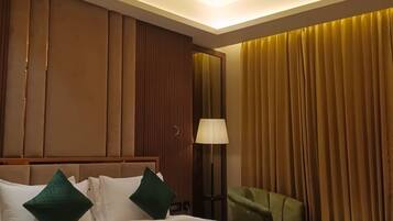 A hotel room with a large bed, a bedside table, a lamp, and a chair.
