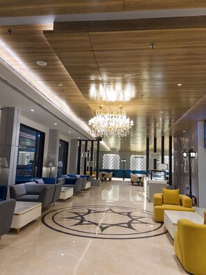 A modern lobby with a wooden ceiling, a large chandelier, and a circular floor design. - Comfort Inn Vindhyan Vindhyachal (Mirzapur)
