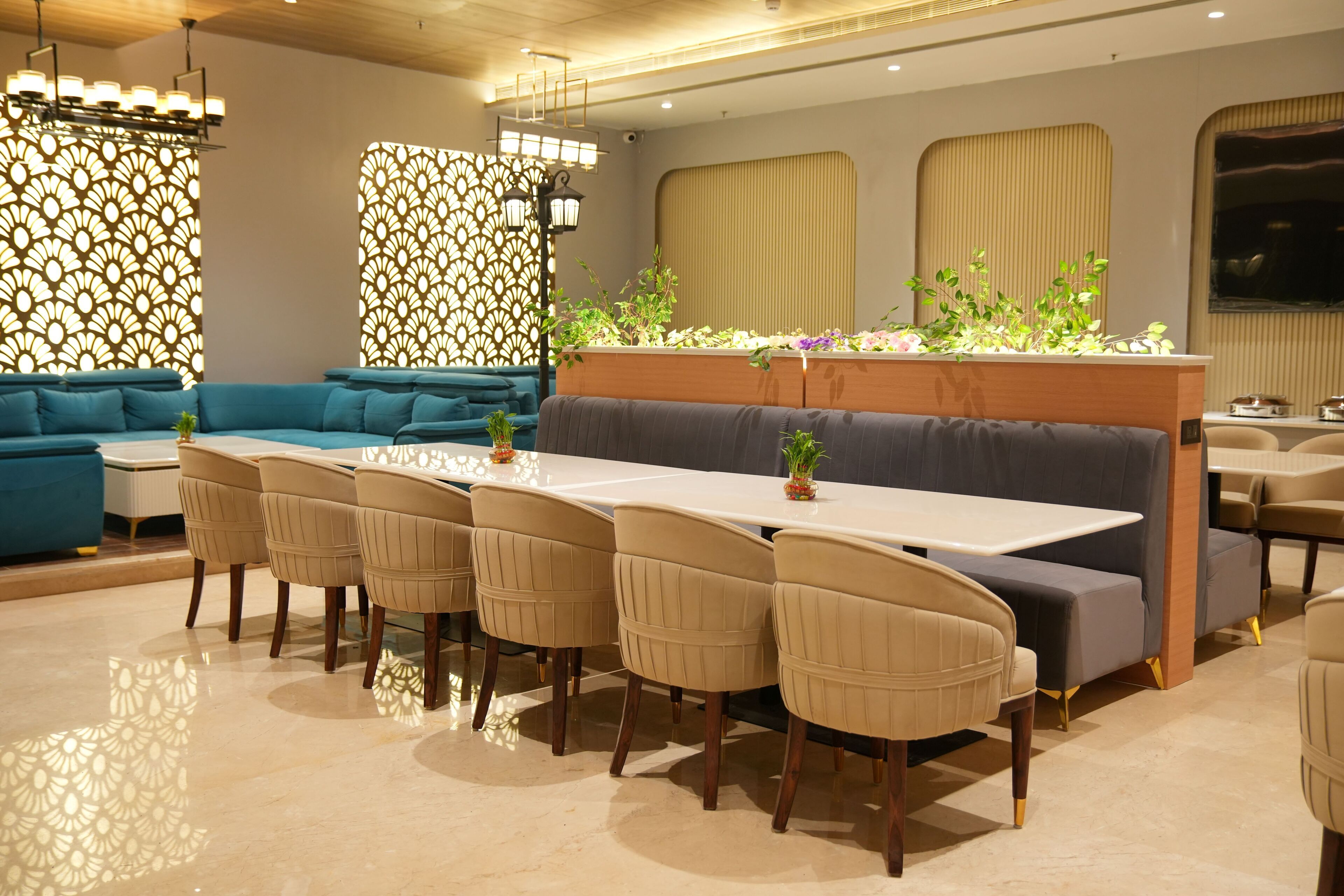 A modern dining area with a long table, beige chairs, and a blue sofa.