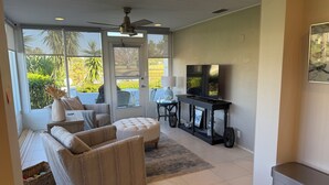 Un salón amplio con un televisor grande, asientos cómodos y vistas al exterior.