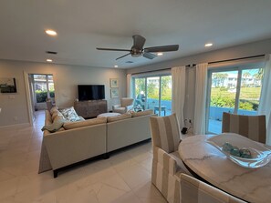 A modern living room with a sofa, armchairs, a TV, and a ceiling fan. - 2-bedroom condo in soothing Venice with cool AC breeze (Venice)