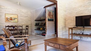 A living room with a wooden coffee table, chairs, a TV, and a bookshelf.