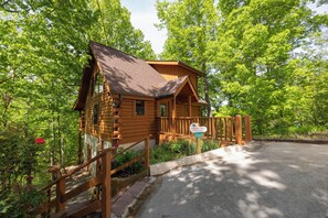 Eine Blockhütte mit Veranda, umgeben von üppigem Grün.