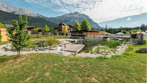 A lakeside cabin with a wooden deck, a small dock, and a mountain backdrop. - Hotel Gerhardhof by ami (Wildermieming)