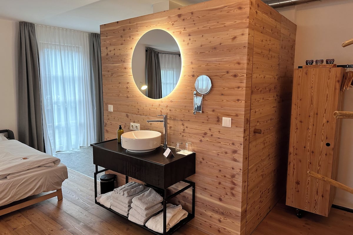 A modern bathroom with a wooden vanity, a round mirror, and a built-in sink.