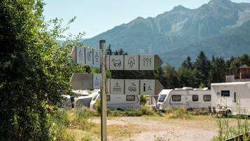 Un panneau de signalisation indiquant la direction à suivre, avec des symboles représentant les commodités disponibles, comme des toilettes, un abreuvoir pour chevaux, un point de restauration et un bureau d’information.