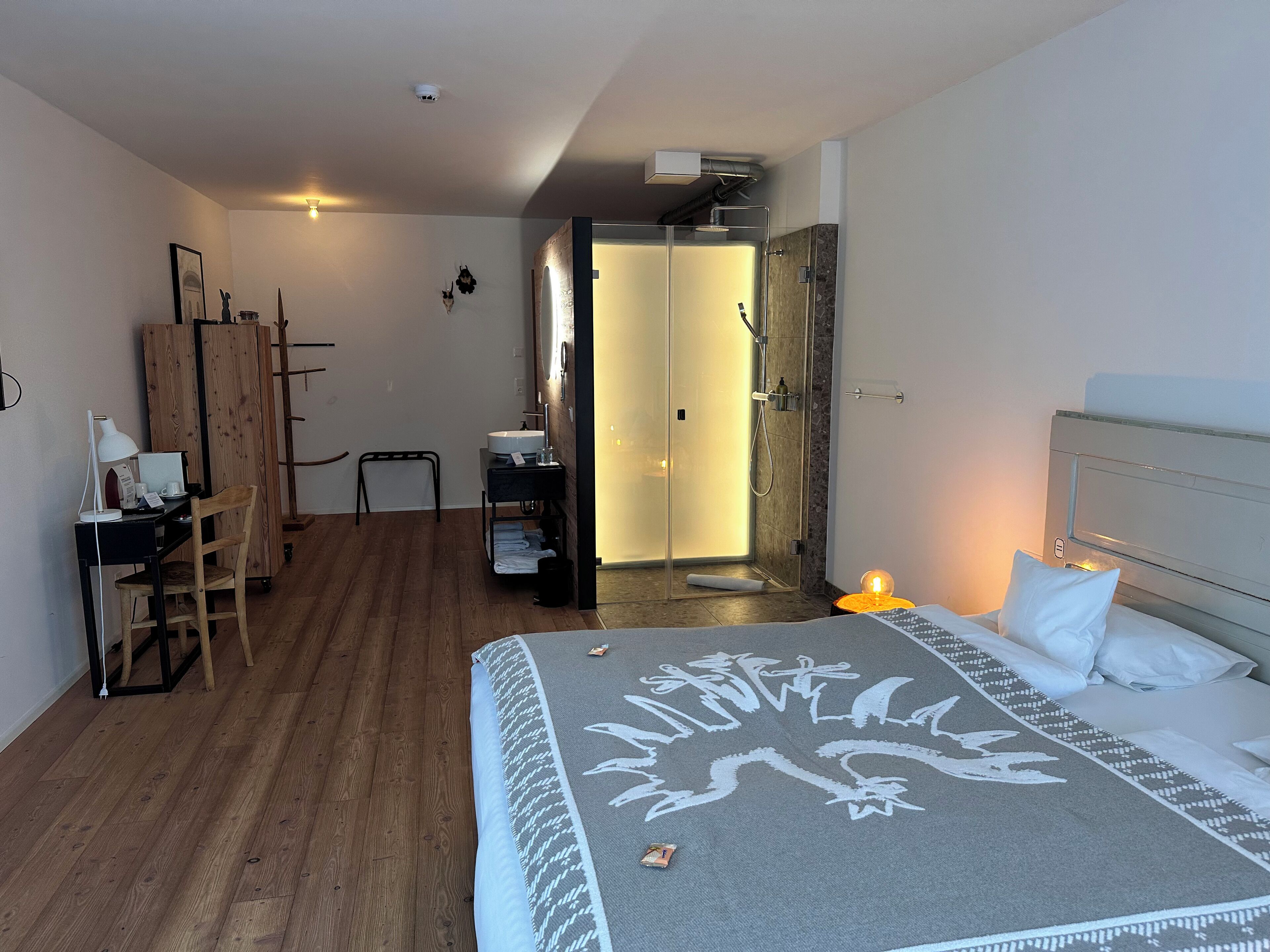 Habitación de hotel con cama, escritorio con computadora, silla, armario y baño con ducha.